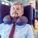 A man wearing travel pillow in airplane